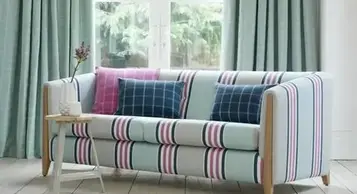 A vibrant striped sofa with pink and blue cushions